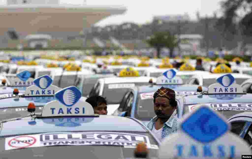 Taxi drivers stand next to parked taxis near the national monument as drivers take part in a protest against what they say is unfair competition from ride-sharing services in Jakarta, Indonesia.