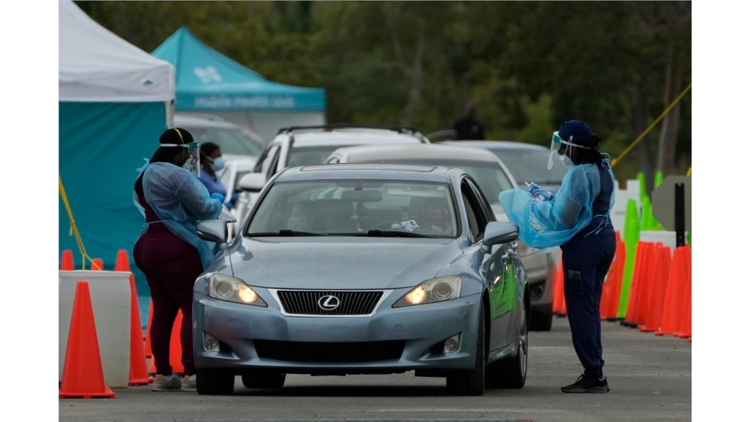 Healthcare workers administer nasal swabs to drivers and passengers at a drive-through COVID-19 testing site at Zoo Miami, Jan. 3, 2022, in Miami.