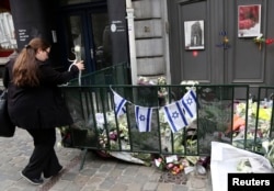 A passer-by places flowers at the entrance of the Jewish Museum in Brussels, Belgium, May 27, 2014.