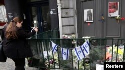 Seorang pejalan kaki meletakkan bunga di pintu masuk Musem Yahudi di Brussels, Belgia, 27 Mei 2014.