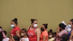 One day ahead of the general elections, women and children stand in line to receive food aid outside government school, Cantarranas, Honduras, Nov. 27, 2021.