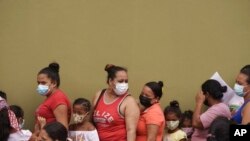 One day ahead of the general elections, women and children stand in line to receive food aid outside government school, Cantarranas, Honduras, Nov. 27, 2021.