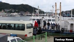 28일 경북 울진 후포항에 도착한 391흥진호 선원이 얼굴을 가린 채 배에서 내려 버스에 타고 있다.