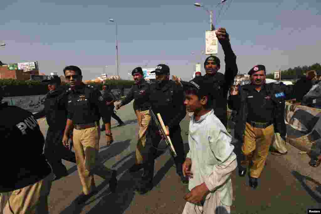 Police walk along a road to disperse residents during a protest against a search operation after the killings of three polio vaccination workers on Tuesday, in Karachi, Jan. 22, 2014.
