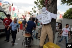 FILE - People pass by an effigy of Fethullah Gulen, a U.S.-based Muslim cleric, with Turkish words that read: "the traitor, FETO " (Feto is the nickname of Fethullah Gulen) in Ankara, Turkey, July 21, 2016.