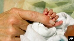 An infant grasps volunteer Kathleen Jones' hand in the neonatal intensive care unit at the University of Chicago's Comer Children's Hospital in Chicago on Wednesday, Feb. 19, 2014. Jones, 52, is one of several people who volunteer to cuddle babies at the hospital. 