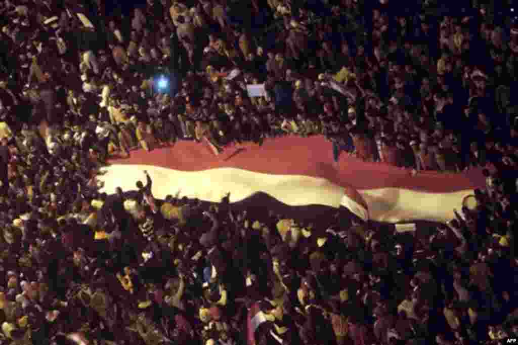 Egyptians wave a giant Egyptian flag at Tahrir Square as they celebrate after President Hosni Mubarak resigned and handed power to the military in Cairo, Egypt, Friday, Feb. 11, 2011. Egypt exploded with joy, tears, and relief after pro-democracy proteste