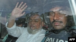 Secretary General of Jamaat-e-Islami, Ali Ahsan Mohammad Mujahid (L) waves from a police vehicle as he is transported to the central jail following his court verdict in Dhaka, Bangladesh, July 17, 2013.