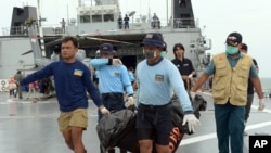 Indonesian's Navy personnel carry a bag containing a dead body of a passenger of AirAsia Flight 8501 at sea off the coast of Pangkalan Bun, Indonesia, Saturday, Jan. 3, 2015.