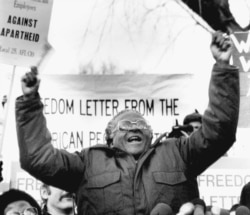 FILE - South African Bishop Desmond Tutu waves during a speech against apartheid, to a crowd of demonstrators, on Jan. 8, 1986, outside the South African Embassy in Washington.