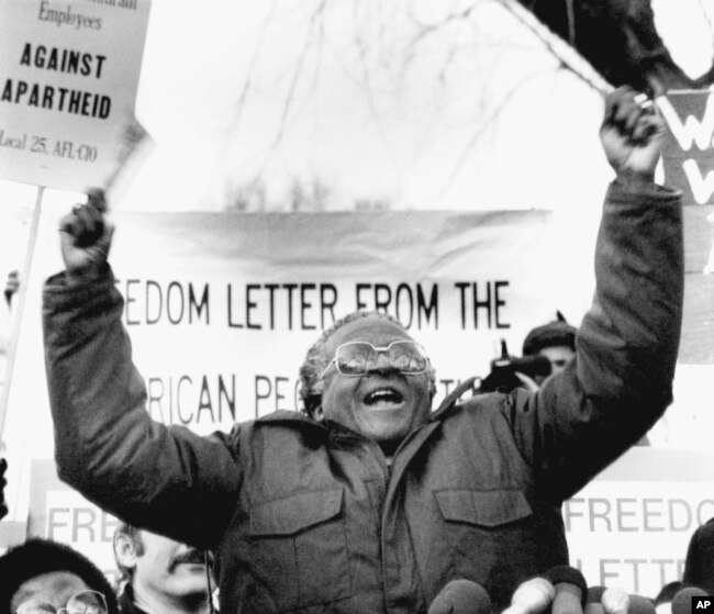 FILE - South African Bishop Desmond Tutu waves during a speech against apartheid, to a crowd of demonstrators, on Jan. 8, 1986, outside the South African Embassy in Washington.