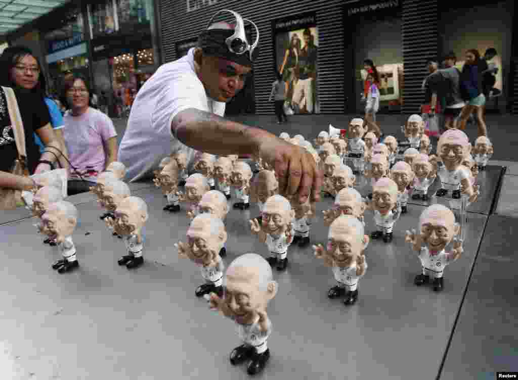 Christopher &quot;Tree Wizard&quot; Pereira, a miniature model craftsman who calls himself a political artist, showcases part of his latest collection of miniature resin figurines of Singapore&#39;s former Prime Minister Lee Kuan Yew along a shopping street in Singapore.