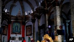 Chinese women walk past a decoration displaying a Baby Jesus doll part of a Nativity scene, at the Nantang Catholic Church in Beijing, China, Dec. 28, 2016.