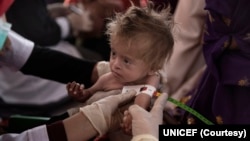 During a mobile health and nutrition team visit in Nasaji village, a nutrition nurse measures arm circumference of a child to determine their nutritional status in Nasaji village in Kandahar province, Afghanistan.