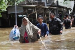 Warga berpegangan pada tali untuk melalui jalanan yang tergenang banjir di Tangerang, Banten, Kamis (2/1).