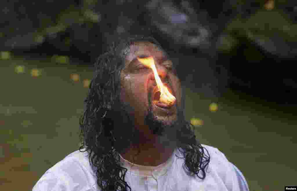 Seorang warga Hindu melakukan aksi memasukkan kamper yang terbakar ke mulutnya dalam acara ritual di Blanchisseuse, Trinidad.