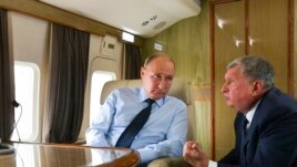 FILE - Russian President Vladimir Putin, left, listens to Russian Rosneft CEO Igor Sechin during his flight to visit Chernigovets coal mine, in Beryozovsky, Kemerovo region, Russia, Monday, Aug. 27, 2018.
