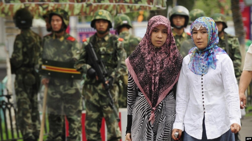 资料照：在新疆乌鲁木齐市的两名维吾尔族妇女步行经过中国武警队伍。 (photo:VOA)