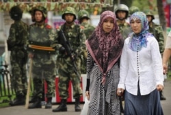 2009年7月14日两名维吾尔族妇女在中国新疆乌鲁木齐市经过警察岗哨。