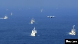 An aerial photo from Kyodo News shows Chinese ocean surveillance, fishery patrol ships and a Japan Coast Guard patrol ship (R and 2nd L) sailing about 27 km (17 miles) west from a group of disputed islands in the East China Sea, September 18, 2012.