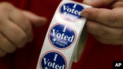 FILE - An election official holds a role of stickers at a polling place in West Columbia, S.C., Feb. 20, 2016. Republican and Democratic presidential candidates compete in primaries and caucuses in least 11states and one U.S. territory Tuesday.