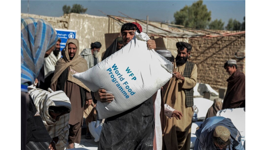 Warga Afghanistan membawa karung-karung berisi makanan yang dibagikan sebagai bantuan Program Pangan Dunia (WFP) di Kandahar pada 19 Oktober 2021. (Foto: AFP/Javed Tanveer)