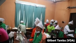 Des employées en train de suivre des explications de la patronne dans la salle de production des coussins menstruels à Minna, la capitale de l‘Etat du Niger, à 160 km d’Abuja, Nigeria, 13 octobre 2018. (VOA/Gilbert Tamba)