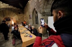 Seorang pria memotret dengan ponsel, saat iftar Ramadan di gereja Santa Anna, Barcelona, Spanyol, di tengah pandemi COVID-19, 28 April 2021. (REUTERS / Albert Gea)