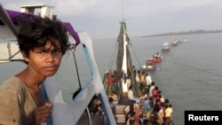 A fishing boat carrying Rohingya and Bangleshi migrants is pulled to shore by Achenese fisherman off the coast of Julok, in Aceh province, May 20, 2015.