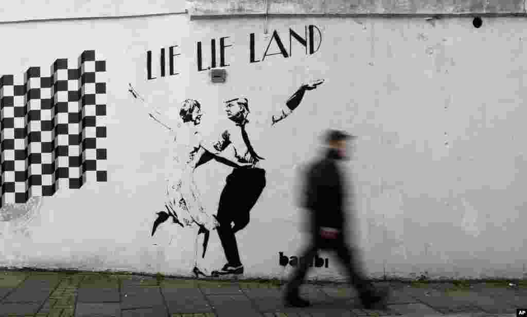 A pedestrian passes a new piece of art by street artist Bambi in London.