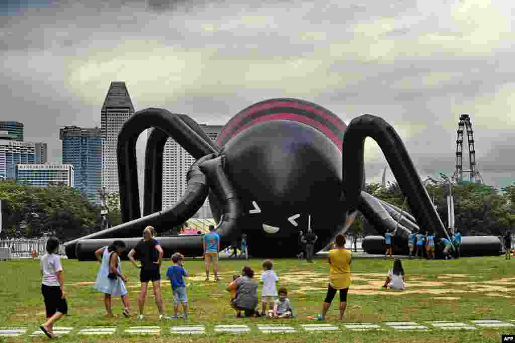 People watch as workers inflate a near-10 meter-high giant spider by Singaporean artist Jackson Tan in Singapore&rsquo;s Marina Bay financial district.