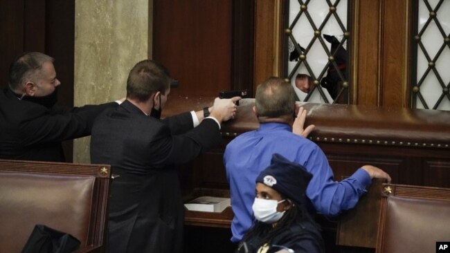 Protesters walk as U.S. Capitol Police officers watch in a hallway near the Senate chamber at the Capitol in Washington, Wednesday, Jan. 6, 2021, near the Ohio Clock. (AP Photo/Manuel Balce Ceneta)