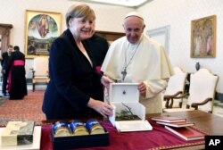Pope Francis and German Chancellor Angela Merkel exchange gifts on the occasion of their private audience, at the Vatican, June 17, 2017.