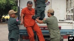 FILE PHOTO - Yem Chroeum, center, an unlicensed medical practitioner, is assisted by prison guards to get off a truck upon his arrival at the Battambang provincial court in Battambang province, northwest of Phnom Penh, Cambodia, Thursday, Dec. 3, 2015. 