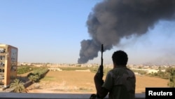 Seorang pejuang dari brigade Zintan menonton asap yang membumbung setelah roket diledakkan oleh salah satu militan Libya dan meledakkan tank minyak di Tripoli, 2 Agustus 2014. 