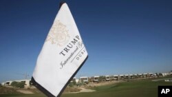 In this Tuesday, Dec. 20, 2016 photo, a flag flies on a green lined with villas at the Trump International Golf Club, in Dubai, United Arab Emirates.