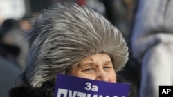A demonstrator holds a poster reading: "For Putin!" during a rally in support of Putin's candidacy to the presidency in the March 4th election, in St.Petersburg, Russia, Saturday, Feb. 18, 2012.