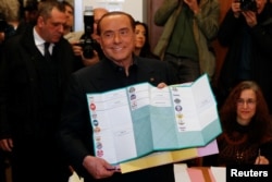 Forza Italia party leader Silvio Berlusconi holds his ballot as he prepares to cast his vote at a polling station in in Milan, Italy, March 4, 2018.