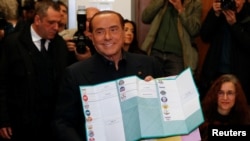 Forza Italia party leader Silvio Berlusconi holds his ballot as he prepares to cast his vote at a polling station in in Milan, Italy, March 4, 2018. 
