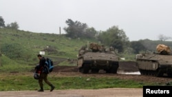FILE - An Israeli soldier walks past armored Israeli military vehicles in the Israeli-occupied Golan Heights, March 25, 2019.