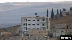 An Islamic State flag is seen atop a building in eastern Kobani, as seen from the Turkish border crossing of Mursitpinar as Kurdish Peshmerga forces fight against Islamic state fighters, Nov. 1, 2014. 