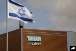 FILE - An Israeli flag flies outside a Teva Pharmaceutical Industries building, in Neot Hovav, Israel, Dec. 14, 2017.