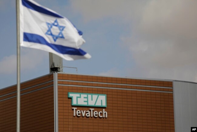 FILE - An Israeli flag flies outside a Teva Pharmaceutical Industries building, in Neot Hovav, Israel, Dec. 14, 2017.