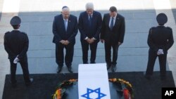 Former US President Bill Clinton, center, accompanied by Israel's President Reuven Rivlin, left, and Yuli Edelstein, the Speaker of the Knesset, pays respects by the coffin of former Israeli President Shimon Peres at the Knesset plaza in Jerusalem, Sept. 