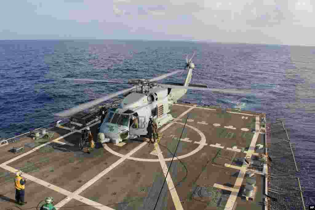 Um helicóptero da Marinha americana aterra no porta-aviões Destroyer USS Pinckney durante a mudança de equipas de busca na missão para encontrar o avião desaparecido da Malaysia Airlines, relativo ao vôo MH370, no Golfo da Tailândia, Domingo, Março 9, 2014.