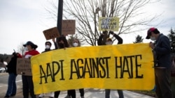 People wave a large "AAPI Against Hate" sign at honking cars during a pre-planned rally against anti-Asian hate crimes held by the Asian American Pacific Islanders Organizing Coalition Against Hate and Bias in Newcastle, Washington, U.S.