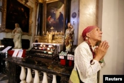 A woman prays as she attends a mass at the Cathedral Sainte Reparate of Nice to pay tribute to victims the day after a truck ran into a crowd at high speed killing scores and injuring more who were celebrating the Bastille Day national holiday.