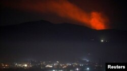 Smoke rises past a mountain as seen from Damascus countryside, Syria, Dec. 25, 2018. 