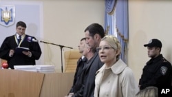 Former Ukrainian Prime Minister Yulia Tymoshenko speaks during her trial, with Judge, Rodion Kireyev, left, reading the indictment at the Pecherskiy District Court in Kiev, Ukraine, October 11, 2011.