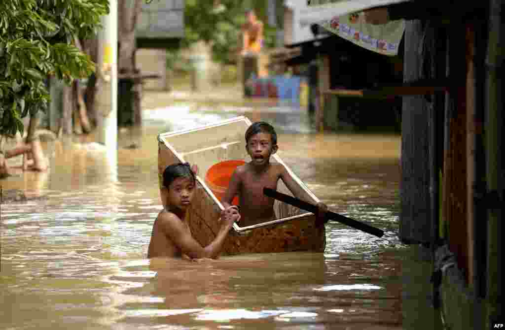 Children use a refrigerator as a boat to cross a flooded alley in Candaba, Pampanga, north of Manila, the Philippines. Vast swaths of farmlands inundated by Typhoon Koppu in October were flooded again this week by rains from Typhoon Melor and the flooding could worsen or spread to other areas as second storm in less than a week threatens the country.